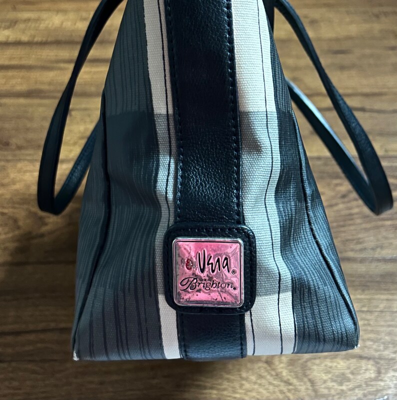 May include: A black and white striped tote bag with a black leather trim and a silver and pink logo that reads "Vera Brighton".
