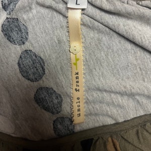 May include: A gray and white polka dot shirt with a brown trim. The shirt has a tag that says "Uncle Frank" and "L" for size.