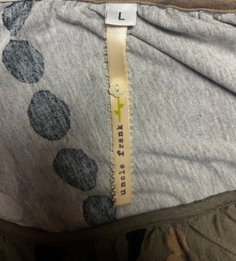May include: A gray and white polka dot shirt with a brown trim. The shirt has a tag that says "Uncle Frank" and "L" for size.