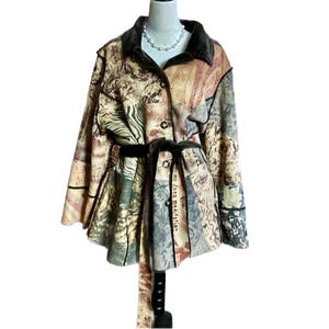May include: A long-sleeved jacket featuring a multi-patterned design in shades of brown, beige, and cream. The jacket has a dark brown collar, a button-front closure, and a matching fabric tie belt at the waist. The fabric displays various prints including floral motifs, text, and abstract patterns.
