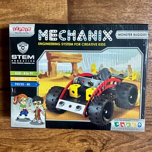 May include: A box for a STEM education toy called Mechanix Monster Buggies. The box shows a red and black toy car with yellow accents. The box says "Engineering System for Creative Kids" and "Age 8 to 99".