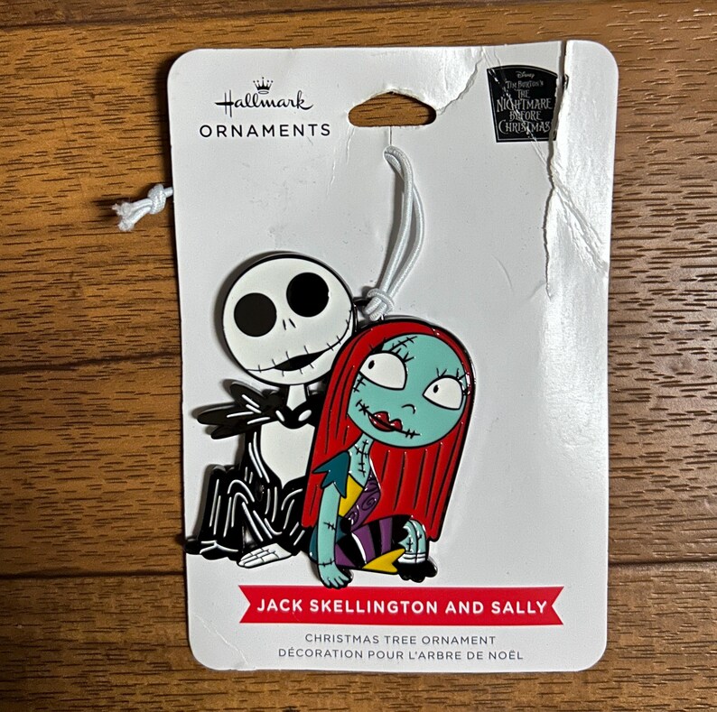 Puede incluir: Adorno navide&ntilde;o Hallmark con Jack Skellington y Sally de The Nightmare Before Christmas. El adorno tiene una cuerda blanca para colgar. El texto "Jack Skellington and Sally" est&aacute; impreso en la parte inferior.