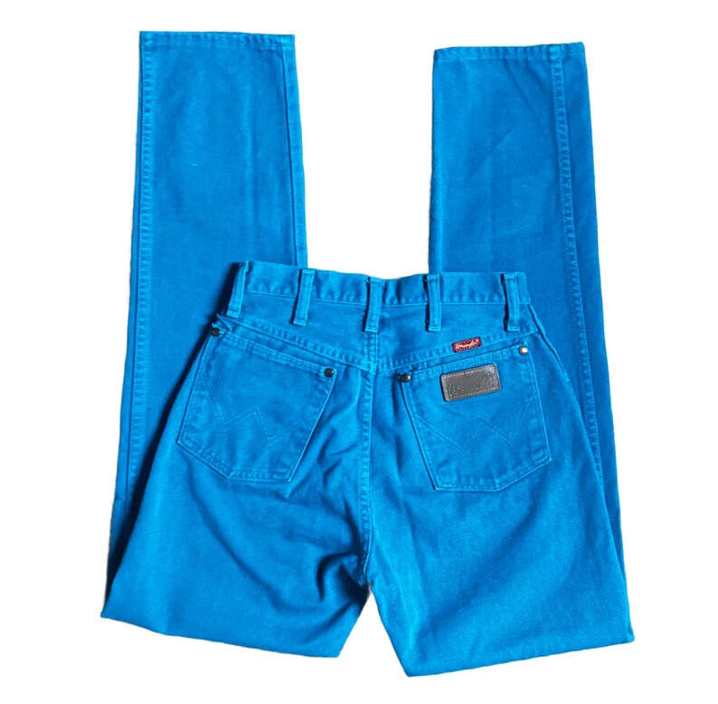 K&ouml;nnte beinhalten: Hellblaue Jeans mit klassischem F&uuml;nf-Taschen-Design. Die Jeans haben einen Wrangler-Markenaufn&auml;her auf der Ges&auml;&szlig;tasche und ein rotes Logo-Etikett. Die Jeans sind einfarbig und haben ein gerades Bein.