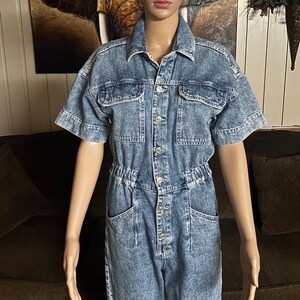 Peut inclure: Une combinaison en jean bleu clair &agrave; manches courtes et fermeture boutonn&eacute;e. La combinaison a une taille cintr&eacute;e et plusieurs poches.