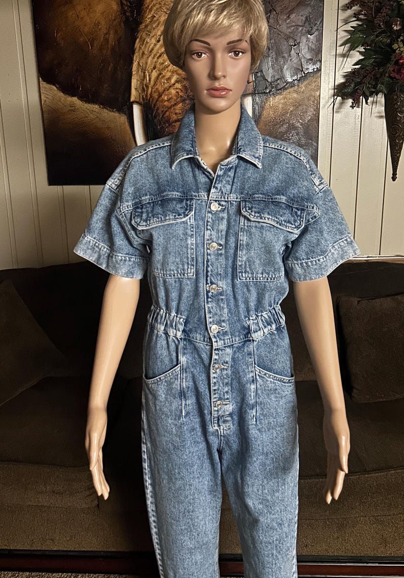 Peut inclure: Une combinaison en jean bleu clair &agrave; manches courtes et fermeture boutonn&eacute;e. La combinaison a une taille cintr&eacute;e et plusieurs poches.