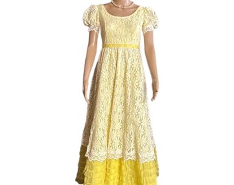 May include: A vintage yellow lace dress with short, puffed sleeves and a fitted bodice. The dress features a yellow ribbon belt and a tiered skirt with a ruffled hem. A pearl necklace is worn with the dress.