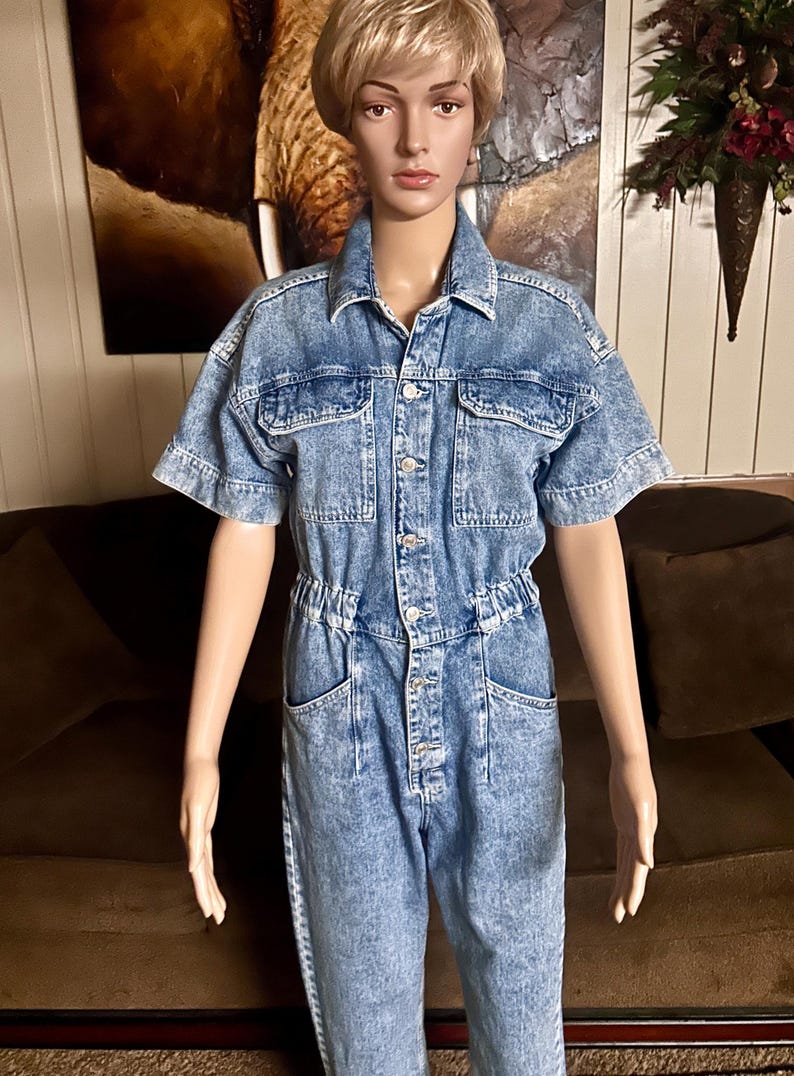 Peut inclure: Une combinaison en jean bleu clair &agrave; manches courtes, avec un devant boutonn&eacute; et plusieurs poches. La combinaison a une taille cintr&eacute;e et une coupe ample.