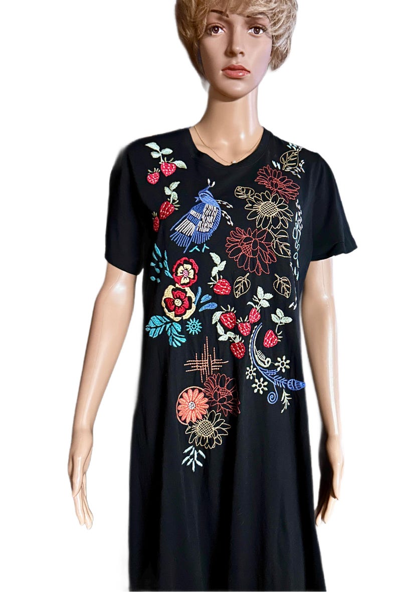 Puede incluir: Una camiseta negra de manga corta con bordados coloridos de un p&aacute;jaro azul, fresas rojas y varios patrones florales en tonos rojo, naranja, amarillo y azul. El dise&ntilde;o se concentra en la parte delantera de la prenda.