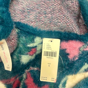 May include: A teal blue and pink fuzzy sweater with a white tag that says "daily PRACTICE" and has the text "C: 4149, V: 008669, S: 0000033, C: TURQ D/F, CP7271 0003, 79297974, SIZE S, $118.00 USD, $138.00 CAD".