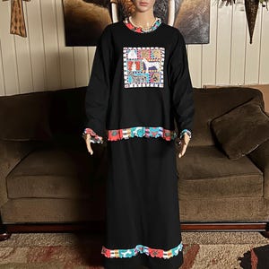 May include: Black long-sleeve dress with a colorful dog-themed graphic on the chest. The dress has a contrasting trim at the neckline, cuffs, and hem. The dress is displayed on a mannequin.