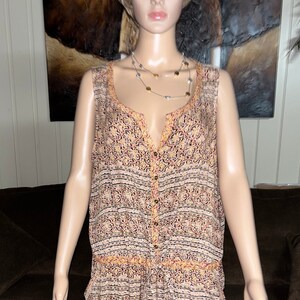 May include: A sleeveless, button-down jumpsuit with a colorful, geometric print. The jumpsuit has a V-neck and a relaxed fit.