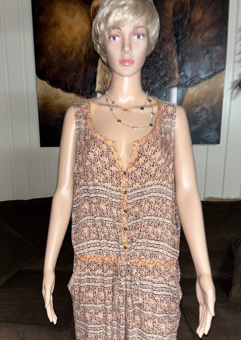 May include: A sleeveless, button-down jumpsuit with a colorful, geometric print. The jumpsuit has a V-neck and a relaxed fit.