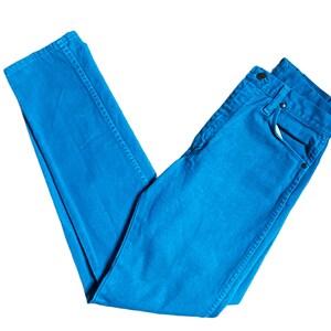 K&ouml;nnte beinhalten: Hellblaue Jeans aus Denim. Die Jeans sind gefaltet und zeigen die Vordertaschen, den Knopf und den Rei&szlig;verschluss. Der Stoff hat eine einfarbige Farbe, mit sichtbaren N&auml;hten entlang der N&auml;hte. Die Jeans sind ein klassischer, l&auml;ssiger Stil.
