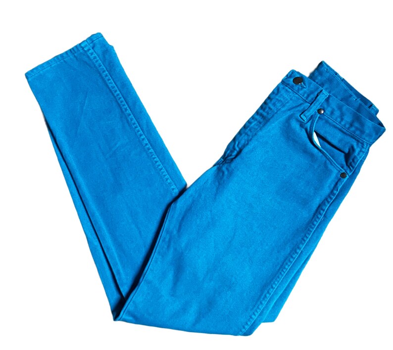 K&ouml;nnte beinhalten: Hellblaue Jeans aus Denim. Die Jeans sind gefaltet und zeigen die Vordertaschen, den Knopf und den Rei&szlig;verschluss. Der Stoff hat eine einfarbige Farbe, mit sichtbaren N&auml;hten entlang der N&auml;hte. Die Jeans sind ein klassischer, l&auml;ssiger Stil.
