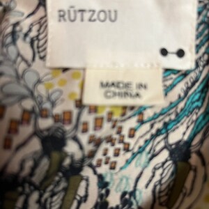 Puede incluir: Una etiqueta blanca con el texto "R&Uuml;TZOU" en letras negras. Debajo del texto hay una etiqueta blanca m&aacute;s peque&ntilde;a con el texto "MADE IN CHINA" en letras negras.