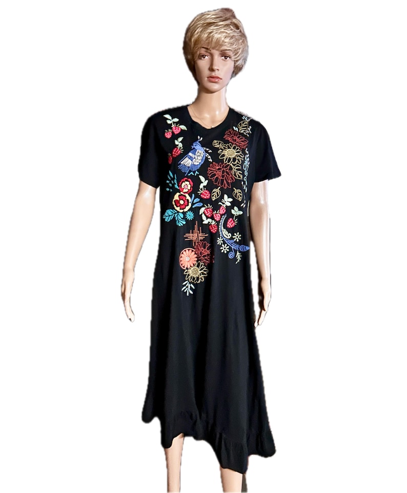Puede incluir: Un vestido midi negro de manga corta con cuello redondo y dobladillo con volantes. La parte delantera del vestido est&aacute; decorada con bordados coloridos que representan varias flores, hojas verdes, fresas rojas peque&ntilde;as y un p&aacute;jaro azul.