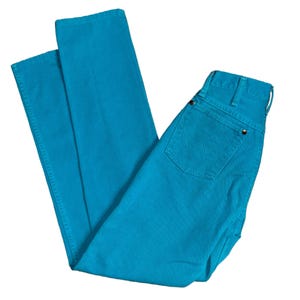 K&ouml;nnte beinhalten: Helle t&uuml;rkisfarbene Jeans. Die Jeans haben ein klassisches F&uuml;nf-Taschen-Design, einen Knopf- und Rei&szlig;verschluss und ein gerades Bein. Die Ges&auml;&szlig;tasche hat ein aufgesticktes Design. Die Jeans sind gefaltet und auf wei&szlig;em Hintergrund dargestellt.