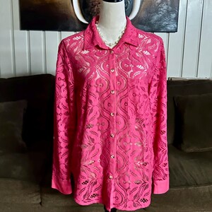 May include: A pink lace button-up shirt with long sleeves. The shirt has a delicate floral pattern and is semi-sheer.