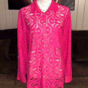 May include: A pink lace button-up shirt with long sleeves and a floral pattern.