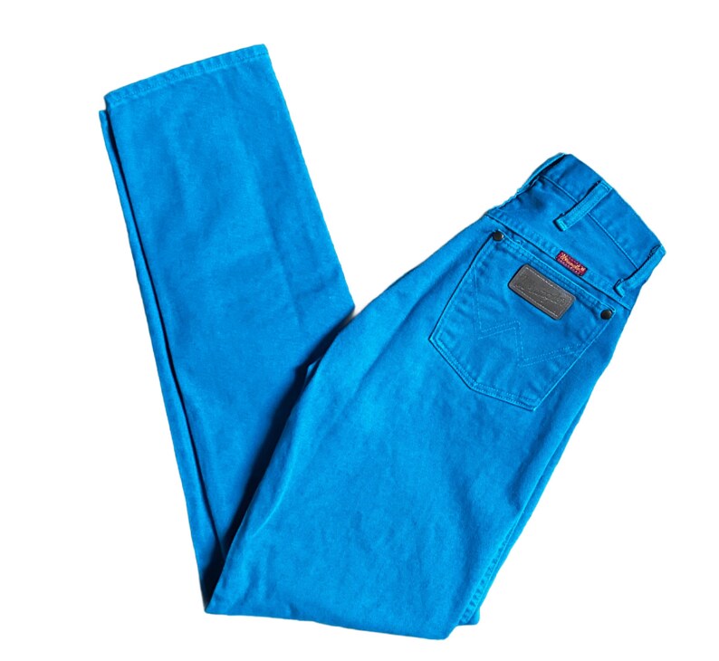 K&ouml;nnte beinhalten: Hellblaue Wrangler-Jeans. Die Jeans haben ein klassisches F&uuml;nf-Taschen-Design, einen braunen Lederaufn&auml;her auf der Ges&auml;&szlig;tasche und das Wrangler-Logo. Die Jeans bestehen aus strapazierf&auml;higem Denim-Material.