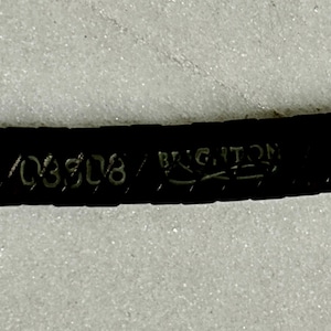 K&ouml;nnte beinhalten: Nahaufnahme eines dunkelbraunen Lederg&uuml;rtels mit dem Markennamen "BRIGHTON" und der gepr&auml;gten Nummer "03508". Der G&uuml;rtel befindet sich vor einem hellen, strukturierten Hintergrund.