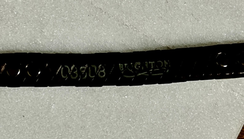 K&ouml;nnte beinhalten: Nahaufnahme eines dunkelbraunen Lederg&uuml;rtels mit dem Markennamen "BRIGHTON" und der gepr&auml;gten Nummer "03508". Der G&uuml;rtel befindet sich vor einem hellen, strukturierten Hintergrund.