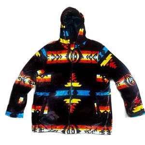 May include: A black hooded jacket with a colorful geometric pattern in red, yellow, and blue. The jacket has a full zipper and two pockets. The cuffs and hood lining are blue.