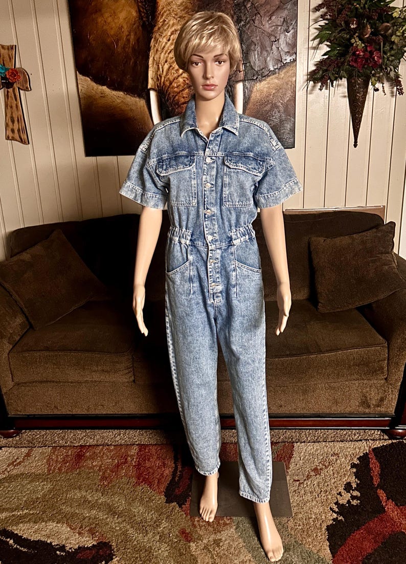 Peut inclure: Une combinaison en jean bleu clair &agrave; manches courtes et &agrave; fermeture boutonn&eacute;e. La combinaison a une coupe d&eacute;contract&eacute;e et une taille &agrave; cordon.