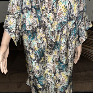 Puede incluir: Un vestido blanco, azul y marr&oacute;n con estampado y cierre de botones en la parte delantera. El vestido tiene un corte holgado y mangas cortas.