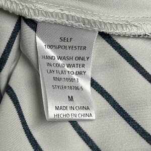 May include: White and black striped fabric with a white tag that says "SELF 100% POLYESTER HAND WASH ONLY IN COLD WATER LAY FLAT TO DRY RN#:105013 STYLE#:18706-5 M MADE IN CHINA HECHO EN CHINA"