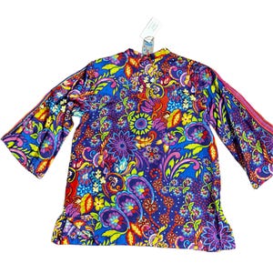 May include: A vibrant, long-sleeved top with a colorful floral and paisley pattern. The top features a blue background with accents of red, yellow, green, and purple. The sleeves are flared, and a tag is attached near the collar.