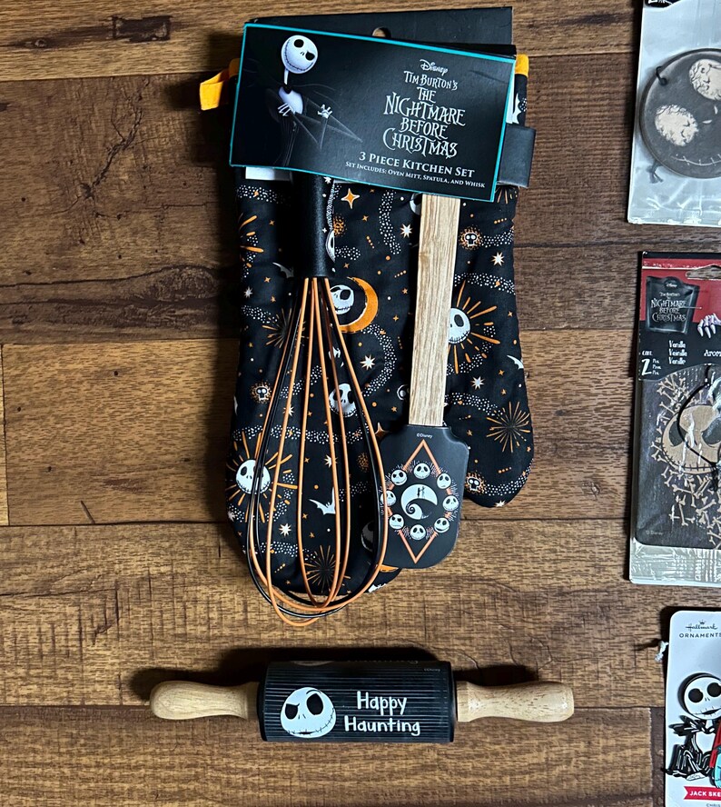 Puede incluir: Un juego de cocina de 3 piezas de Nightmare Before Christmas en negro y naranja. El juego incluye un guante de cocina, una esp&aacute;tula y un batidor. El guante y la esp&aacute;tula presentan dise&ntilde;os de Jack Skellington. Tambi&eacute;n se incluye un rodillo con el texto "Happy Haunting".