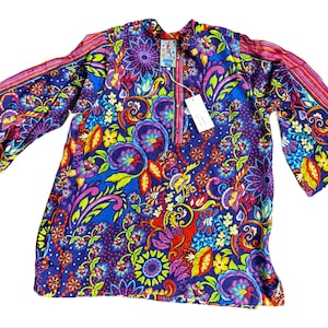 May include: A vibrant, long-sleeved tunic with a colorful floral pattern in shades of blue, purple, red, yellow, and green. The tunic features bell sleeves and a mandarin collar. A tag is attached near the neckline.