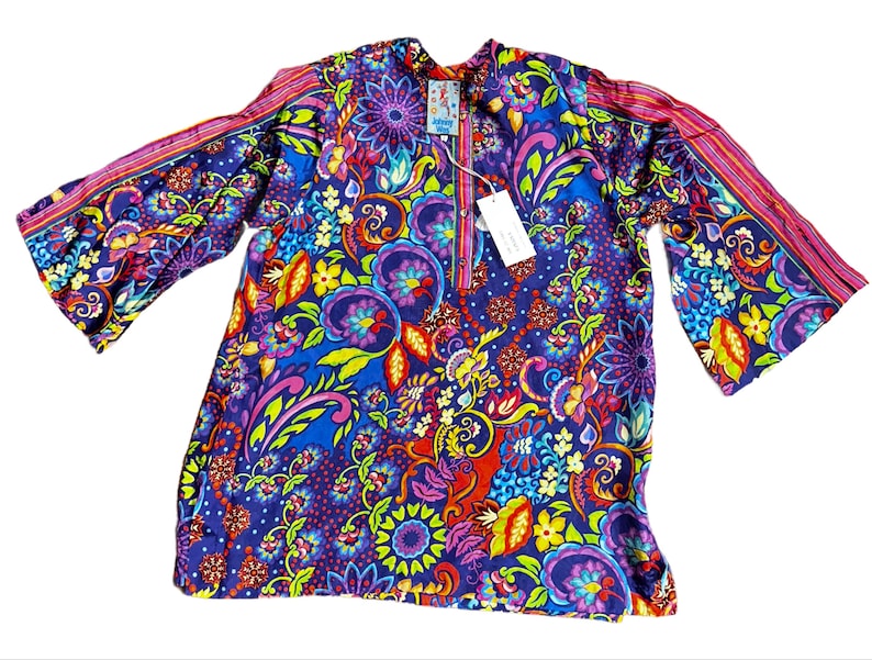 May include: A vibrant, long-sleeved tunic with a colorful floral pattern in shades of blue, purple, red, yellow, and green. The tunic features bell sleeves and a mandarin collar. A tag is attached near the neckline.