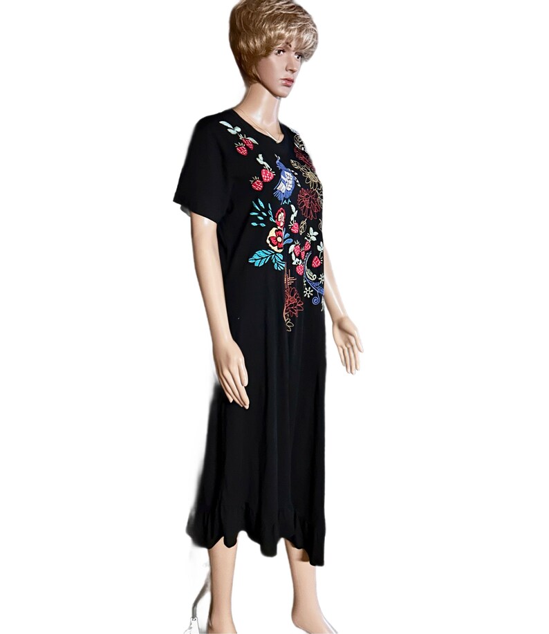 Puede incluir: Un vestido midi negro de manga corta con un dise&ntilde;o bordado colorido en la parte superior delantera. El bordado incluye fresas rojas, p&aacute;jaros azules y varios patrones florales en tonos amarillo, rojo y azul cerceta. Tiene un cuello redondo simple.