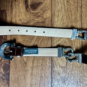 Puede incluir: Dos cinturones de cuero con hebillas plateadas. El cintur&oacute;n superior es beige con una hebilla plateada con un dise&ntilde;o de cuerda. El cintur&oacute;n inferior es marr&oacute;n con una hebilla plateada de dise&ntilde;o sencillo. El cintur&oacute;n inferior tiene la palabra "BRIGHTON" impresa.