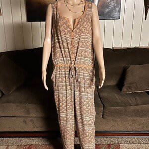 May include: A sleeveless, orange and white patterned jumpsuit with a button-up front and a drawstring waist.