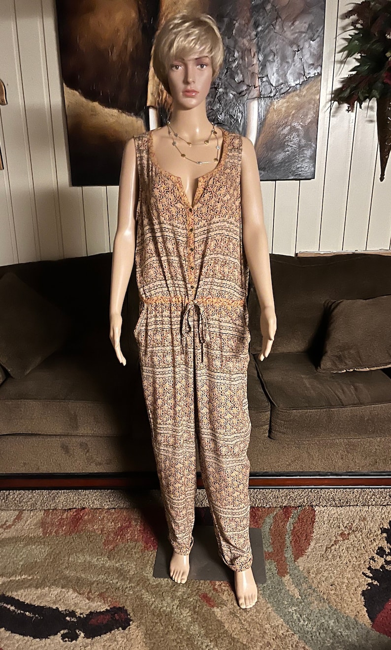 May include: A sleeveless, orange and white patterned jumpsuit with a button-up front and a drawstring waist.