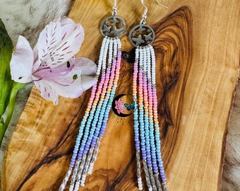 May include: A pair of long, colorful beaded earrings with butterfly charms. The earrings are made with small, colorful beads in shades of pink, blue, and orange. The butterfly charms are silver and are attached to the top of the earrings.