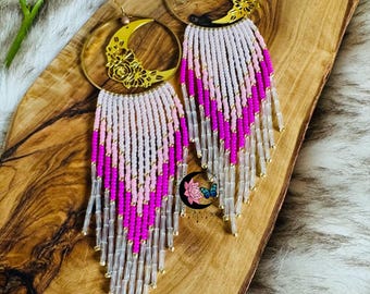 May include: Gold hoop earrings with a crescent moon design and floral details. The earrings are adorned with pink, white, and clear beads that dangle from the hoops.