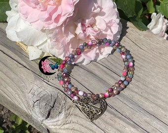 May include: A multi-strand beaded necklace with a heart-shaped pendant. The beads are in shades of pink, purple, and blue. The pendant is made of metal and has a filigree design.