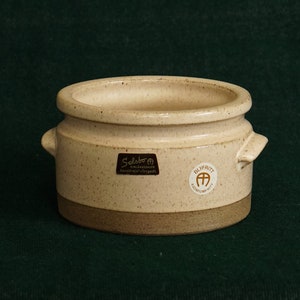 Op de afbeelding: Een klein, wit keramiek potje met twee handvatten. Het potje heeft een bruine rand en een bruin label met de tekst "Sulvern" en "Handmade in England".