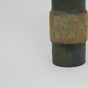 May include: A dark green ceramic vase with a textured band of light green and brown glaze.