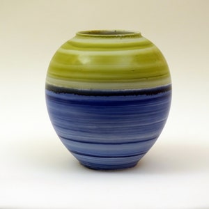May include: A ceramic vase with a rounded shape and a striped design. The top half of the vase is a light green colour with horizontal stripes, and the bottom half is a blue colour with horizontal stripes.