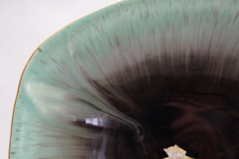 Puede incluir: Un cuenco de cer&aacute;mica con un esmalte verde y negro. El cuenco tiene un borde ancho y un interior profundo y redondeado. El esmalte se aplica en un patr&oacute;n de remolino, creando un dise&ntilde;o &uacute;nico y llamativo.