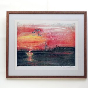 May include: Framed print of a sunset over a body of water with a silhouette of a city skyline in the distance. The sky is a vibrant red and orange with a few white clouds. There are birds flying in the sky. The print is signed "Handel" and "A. Taylor".