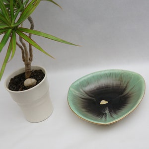 Puede incluir: Un plato de cer&aacute;mica verde y negro con un borde dorado. El plato tiene forma de tri&aacute;ngulo y presenta un patr&oacute;n de espiral.