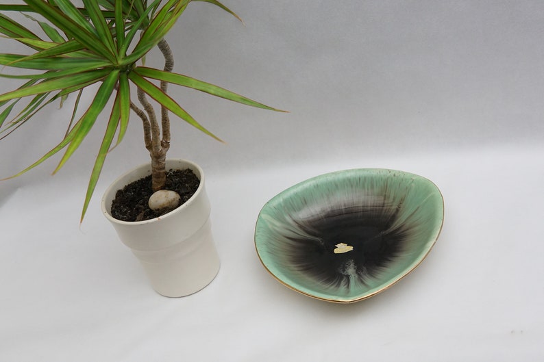 Puede incluir: Un plato de cer&aacute;mica verde y negro con un borde dorado. El plato tiene forma de tri&aacute;ngulo y presenta un patr&oacute;n de espiral.