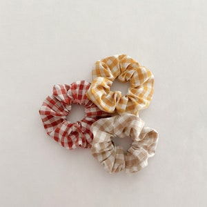 May include: Three gingham hair scrunchies in red, yellow and beige.
