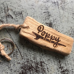 Pu&ograve; includere: Un portachiavi rettangolare in legno galleggiante marrone chiaro con il nome Poppy inciso a fuoco sulla superficie in corsivo. Un anello metallico &egrave; fissato al legno attraverso un piccolo foro utilizzando un pezzo di spago di juta naturale.